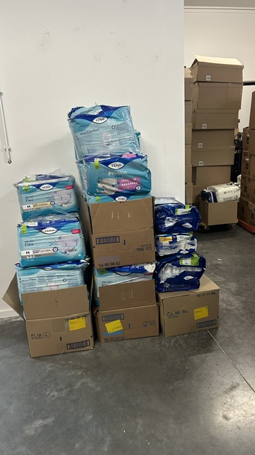 Gestapelde hygiëneproducten zoals incontinentiemateriaal en wondverband in het magazijn van CareCycle, klaar voor hergebruik of donatie.